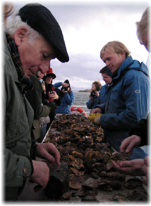 Passengers eagerly wait while staff shuck freshly caught scallops.