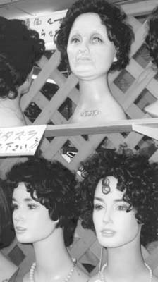 A wig display on Kokusai Street shows an aged model — Naha. Photo: Goodhead