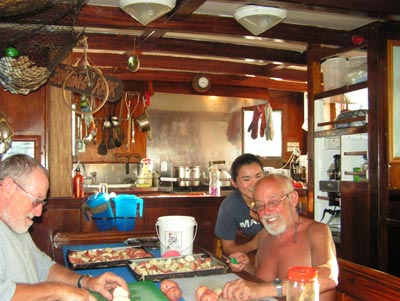 Two members of the Voyage Crew do kitchen duty while a deckhand looks on.