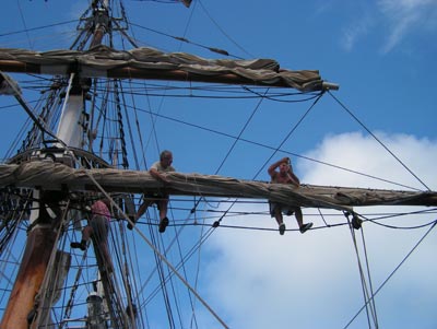 Members of the crew go aloft to release the sails.