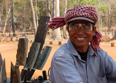 Smiling Khmer salesman of knives, machetes and sling blades at Koh Ker, Cambodia. 