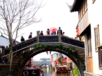 An ancient arched bridge curves over a canal — Suzhou.