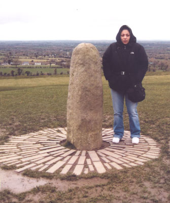 Katie (looking frozen) standing next to the Lia Fáil at the Hill of Tara.
