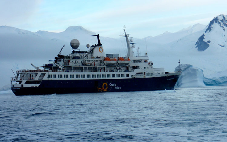 The Sea Adventurer sits at anchor waiting for passengers to return from shore excursions.