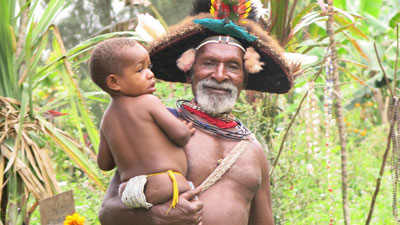A cute pikinini (Pidgin for “child”) in the arms of a Huli wigman.