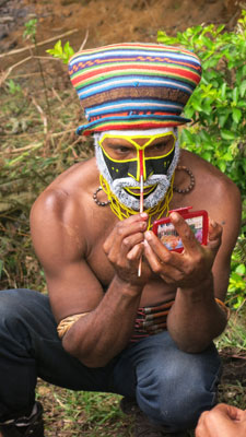 A man applying makeup in preparation for the Tumbuna show.