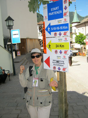 Karen Heady standing next to signs denoting Volksmarches of different routes and paces. 