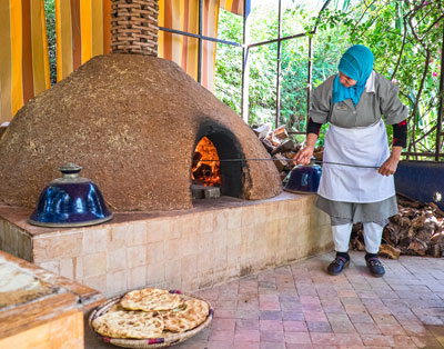 Teacher demonstrating how to cook Moroccan flatbread during a cooking class at La Maison Arabe in Marrakech.