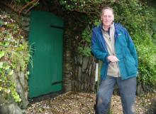 Sir Geoffrey standing near the green door to the Secret Seaside Gardens of Black