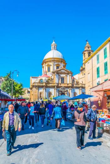 An open-air market with the Baroque backdrop of the Church of Saint Francis Xavier — Palermo, Sicily, Italy.
