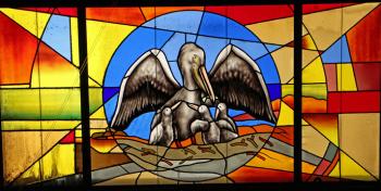 Stained-glass window depicting a pelican and her chicks.