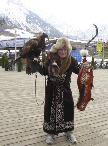 Alan in traditional Kazakh dress holding a golden eagle, high in the mountains near Shymbulak.