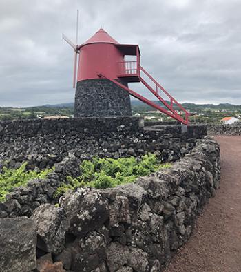 On Pico Island in the Azores, this windmill was formerly used to grind grain. What is interesting is the red part of the windmill can be turned so the blades are always facing the wind. The stairs are hooked to an O-Ring and are simply detached and moved to another O-Ring surrounding the base. Photo by Norman Dailey