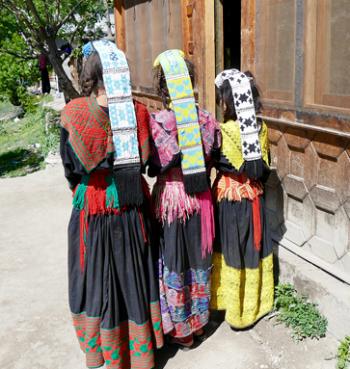 Kalasha girls showing off their elaborate headdresses, with buttons, bells, embroidery and conch shells — Chitrāl district, northern Pakistan.