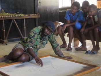 While a docent at the National Museum of Vanuatu created a sand drawing (called <i>sandroing</i> in Bislama) illustrating a folk tale, local boys were entranced — Port Vila, Vanuatu (June 2019). Photo by Esther Perica