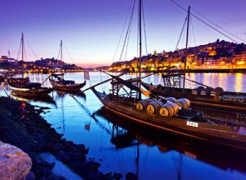 Traditional “rabelo” boats, which were once used to deliver port wine from the Douro Valley, line Porto’s harbor at sunset.