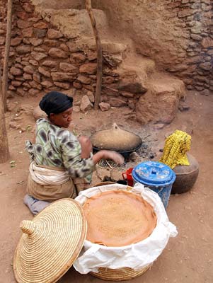 Woman preparing injera pancakes over an open fire.
