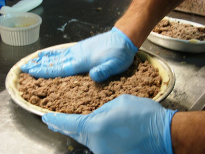 Meat mixture being pressed into the pie shell. 