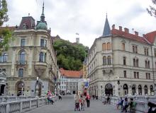 Walking the center span of Ljubljana’s decorative Tromostovje (Triple Bridge) toward hilltop Ljubljana Castle.