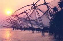 Sun going down behind seven huge, cantilevered fishing nets in the island of Vypin.