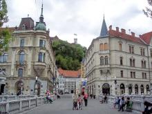 Walking the center span of Ljubljana’s decorative Tromostovje (Triple Bridge) toward hilltop Ljubljana Castle.