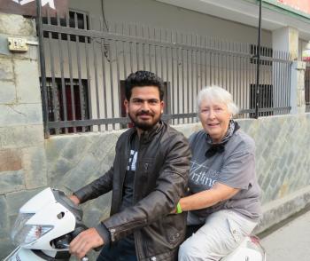 Sue Spirit on a motorbike with school volunteer Deepak.