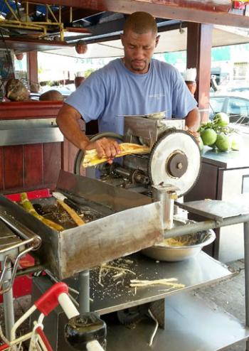 A vendor extracts sweet juice from sugarcane at the Marigot market — Saint-Martin. 