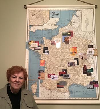 Jan Linkenback beside the map covered with business cards indicating special restaurant experiences in France. Photo by Ron Linkenback