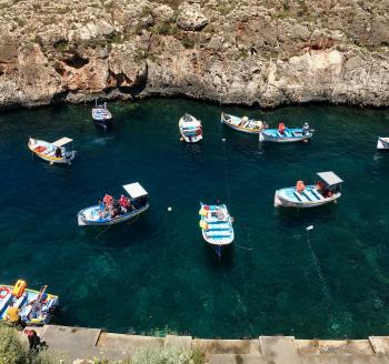 Malta’s Blue Grotto is a very popular tourist spot below a high cliff overlooking the sea.