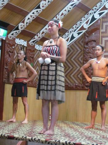 This Māori dancer is wearing a <i>piupiu</i>, a skirt made of flax, and holding poi, small balls of woven flax used while singing and dancing — Te Puia in Rotorua, New Zealand.
