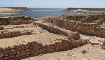 Remains of frankincense storage rooms at Sumhuram, with the sea gate in the middle and the sandbar blocking the former harbor in the background.